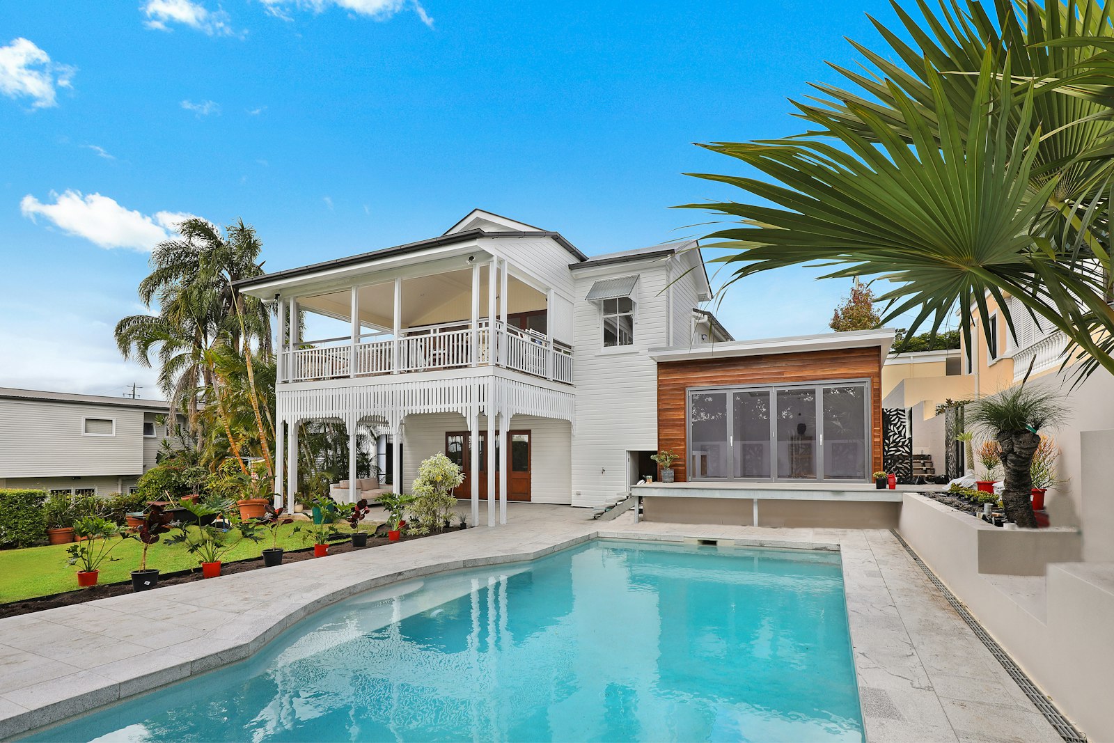 A white two-story house with an open double gallery and a pool court